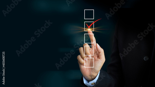 Checking mark on checklist with a red marker on dark background photo