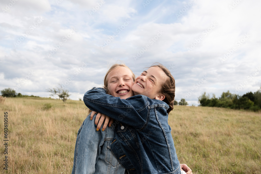 Smiling girl friends hugging in field Smiling girl friends hugging in field