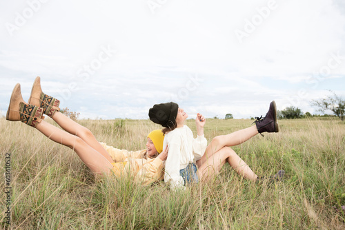 Smiling girl friends sitting in grass