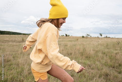 Smiling girl in yellow beanie frolicking in field photo