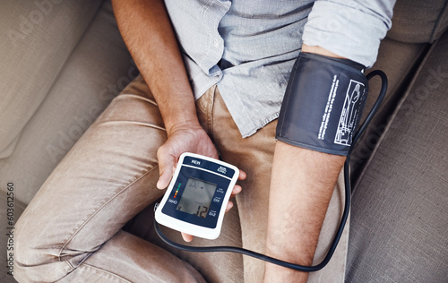 Hypertension, machine and man test blood pressure in a home sofa or living room for medical or health exam. Monitor, reading and person in a lounge equipment for chronic disease due to stress