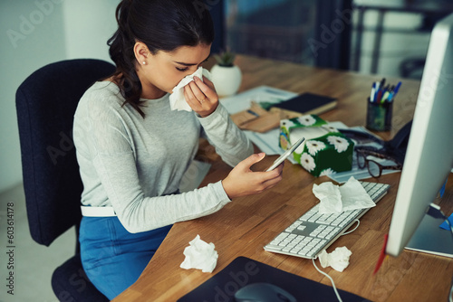 Blowing nose, phone and a business woman working at her desk in the office while sick, ill or unwell. Covid, tissue and allergies with a young female employee typing a mobile text message at work