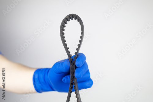 Timing belt cracked. Replacing a failed engine transmission belt. Cracks in rubber and risk of broken cords. Replacement of equipment according to the regulations. Mechanic in blue gloves photo