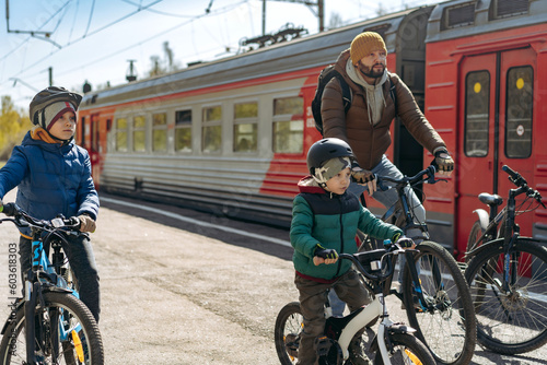 Obraz na plátně man and children on bicycles on train station travelling to countryside
