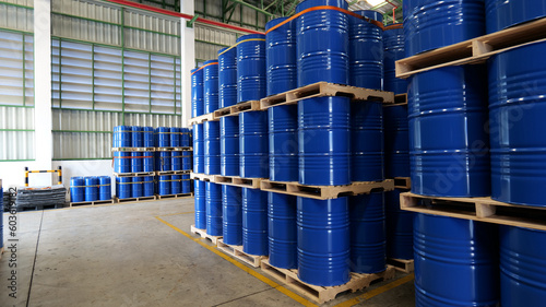 Blue barrel 200 liter chemical drums are stacked on wooden pallets inside the warehouse awaiting delivery. Concept of Chemical industry, petroleum industry and transportation technology