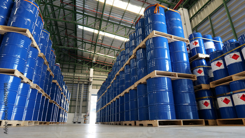 Blue barrel 200 liter chemical drums are stacked on wooden pallets inside the warehouse awaiting delivery. Concept of Chemical industry, petroleum industry and transportation technology