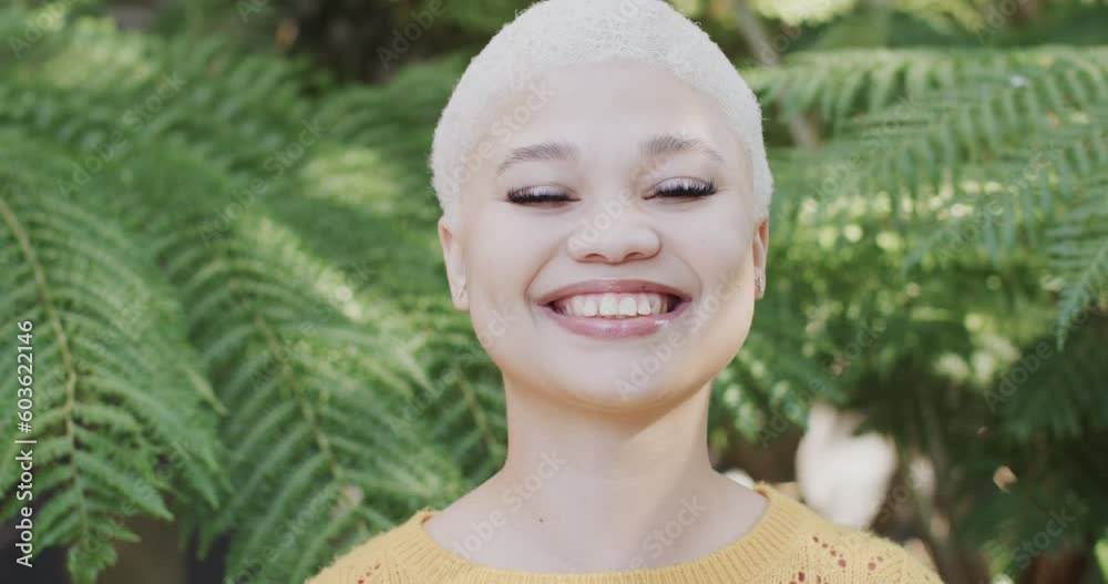 Portrait of happy biracial woman in garden with big green leaves in slow motion