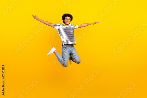 Full body size photo of young jumping handsome guy arms wings flight active time spending have fun isolated on yellow color background