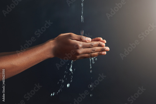 Washing hands, water and person cleaning palm for hygiene isolated in a dark or black studio background. Stream, splash and hand clean for wellness or hydration with germ protection or bacteria
