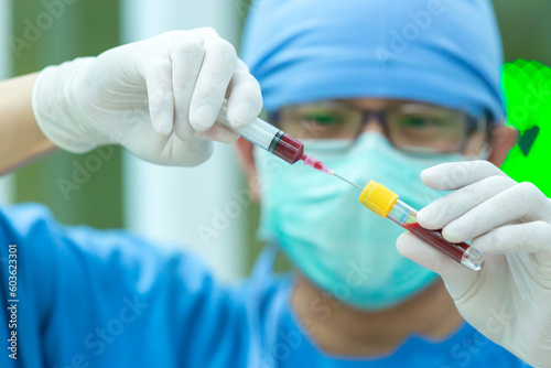 The doctor with a syringe of blood sample and a rack with other samples. Technician holding blood syringe sample for study.