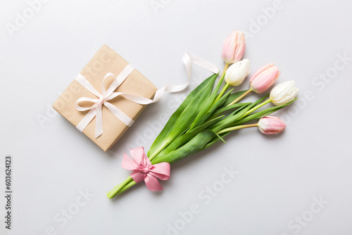 Pink tulips flowers and gift or present box on colored table background. Mothers Day  Birthday  Womens Day  celebration concept. Space for text top view