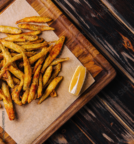wooden board of fried whitebait with slices of lemon