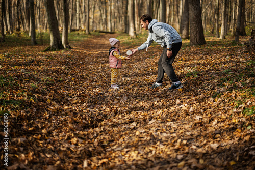 Father play with baby daughter in family leisure at autumn activity in forest.