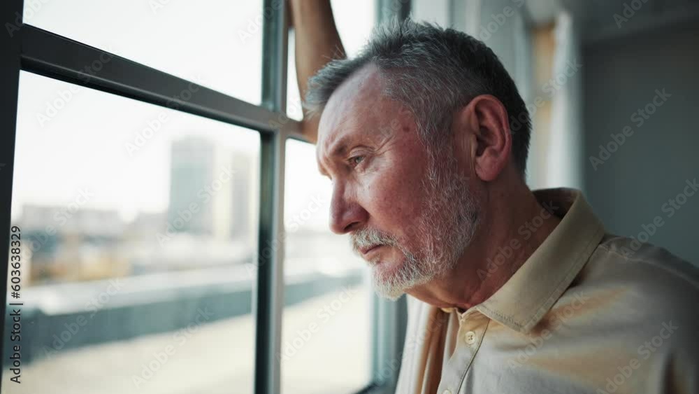 Close up sad elderly man face looking out the window, yearning about past recollect memories. Sad old man crying near window, suffering loneliness, emotions, feelings and spending time at home.