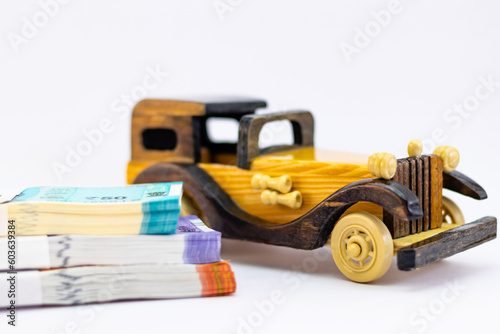 High angle close up shot of money bundles piled up and a wooden vitage car toy in luxury life concept.