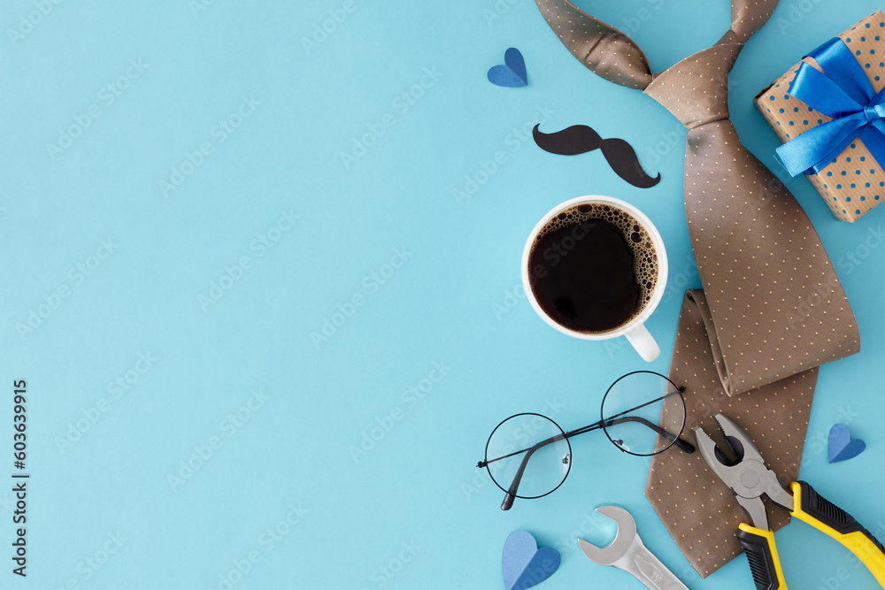 Father's Day celebration concept. Top view flat lay of stylish necktie, glasses, mustache, gift box, cup of coffee and hand tools on light blue background with space for text or special message