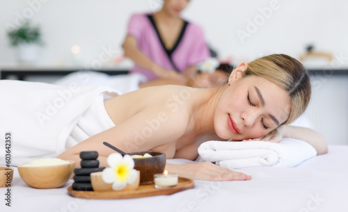 Portrait shot of Millennial Asian young beautiful relaxing resting nude naked woman laying lying down smiling look at camera on comfortable massage bed under clean white towel waiting for masseuse