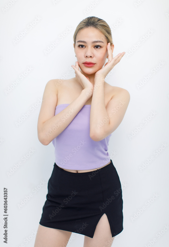 Portrait isolated cutout studio shot of Asian beautiful pretty cheerful female model in tube cropped top shirt standing smiling using hands massaging cream oil moisturizer on face on white background Portrait isolated cutout studio shot of Asian beautiful pretty cheerful female model in tube cropped top shirt standing smiling using hands massaging cream oil moisturizer on face on white background