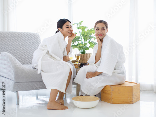 Millennial two Asian young beautiful sexy female friend in white clean towels sitting smiling on chair prepair for aroma therapy relaxation. photo