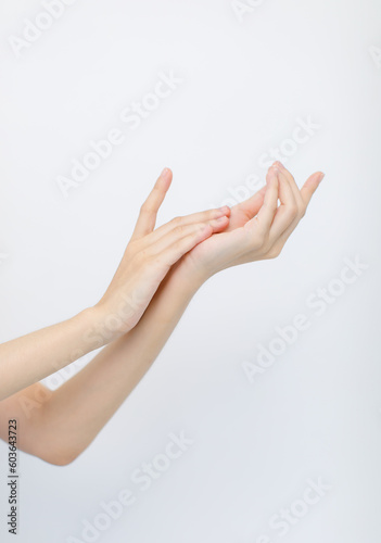 Closeup isolated cutout studio shot of unrecognizable female arms hands using essential cosmatic oil cream moisturizer massaging into beautiful clear clean skin with copy space on white background