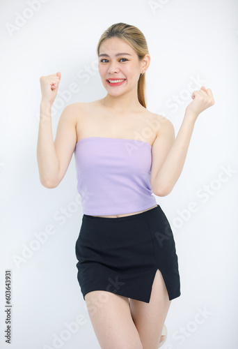 Portrait closeup studio isolated cutout shot of Millennial Asian beautiful pretty cheerful female model in tube cropped top shirt holding fists up exciting smiling look at camera on white background © Bangkok Click Studio