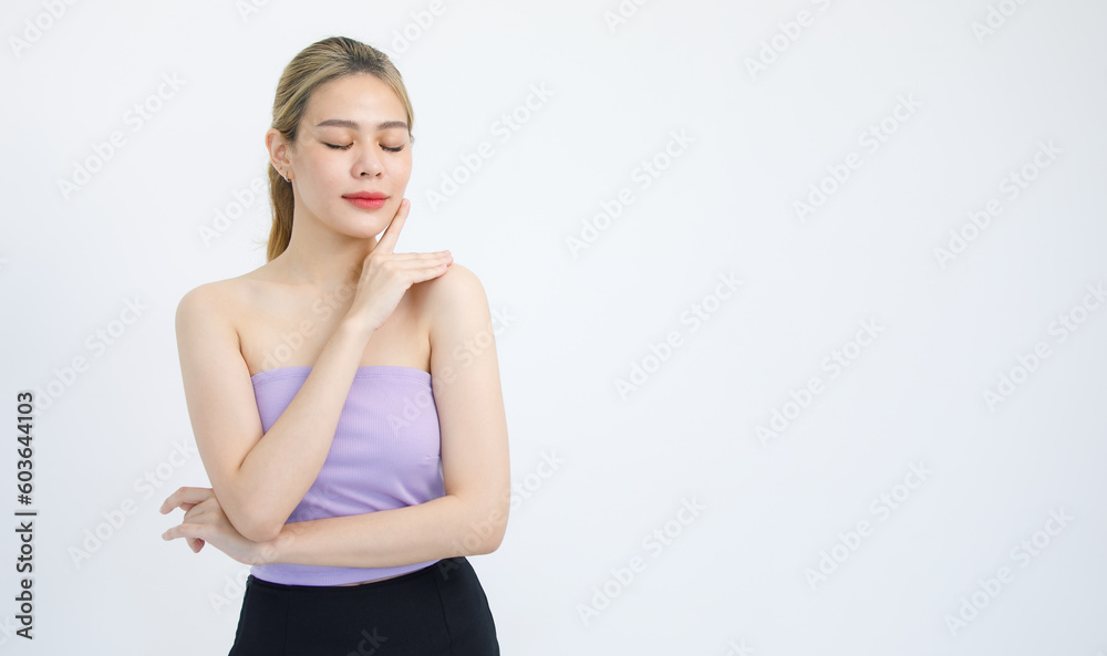 Portrait isolated cutout studio shot of Asian beautiful pretty cheerful female model in tube cropped top shirt standing smiling using hands massaging cream oil moisturizer on face on white background Portrait isolated cutout studio shot of Asian beautiful pretty cheerful female model in tube cropped top shirt standing smiling using hands massaging cream oil moisturizer on face on white background