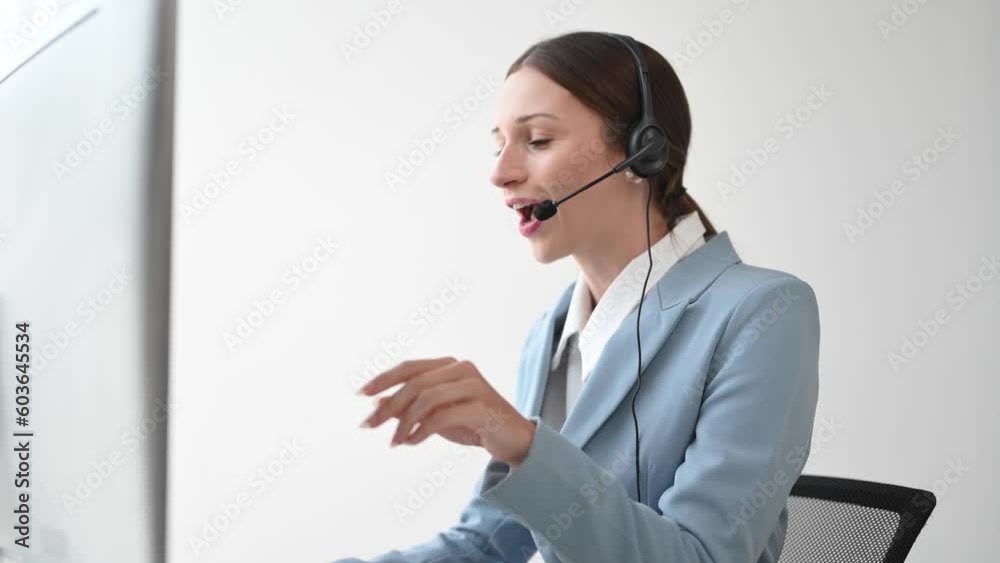 Serious call center operator in wireless headset talking with customer, woman in headphones with microphone consulting client on phone in customer support service in office center Serious call center operator in wireless headset talking with customer, woman in headphones with microphone consulting client on phone in customer support service in office center