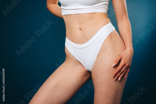 Diet. Cropped image of healthy slim female body, breast, belly on blue studio background. Model posing in white underwear. Concept of body and skin care, fitness, natural beauty, health, wellness