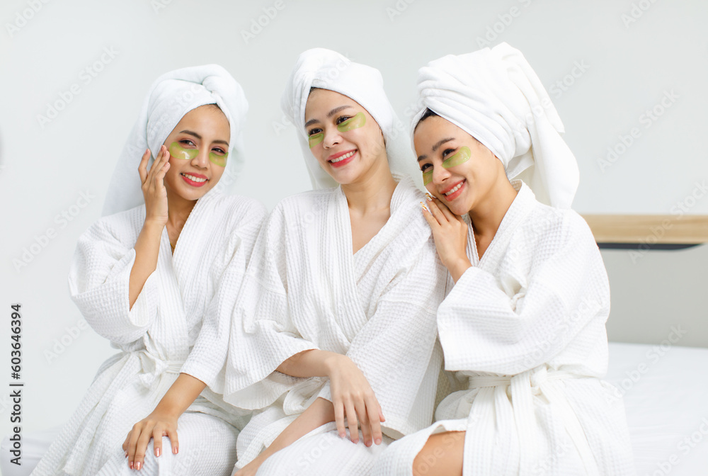 Millennial three Asian female customers friends in white clean bathrobes and towels have appointment at massage resort sitting on chair chit chat talking having conversation together before massaging Millennial three Asian female customers friends in white clean bathrobes and towels have appointment at massage resort sitting on chair chit chat talking having conversation together before massaging