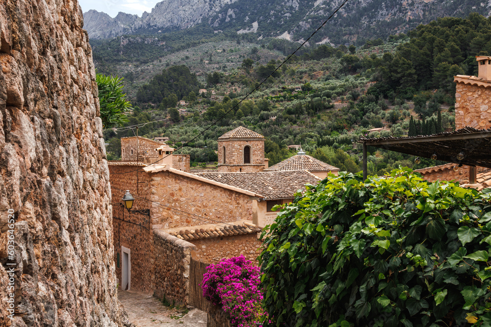 Traditional mountain village Fornalutx in Mallorca. Typical street in a Spanish old town with stone buildings and flowering potted plant