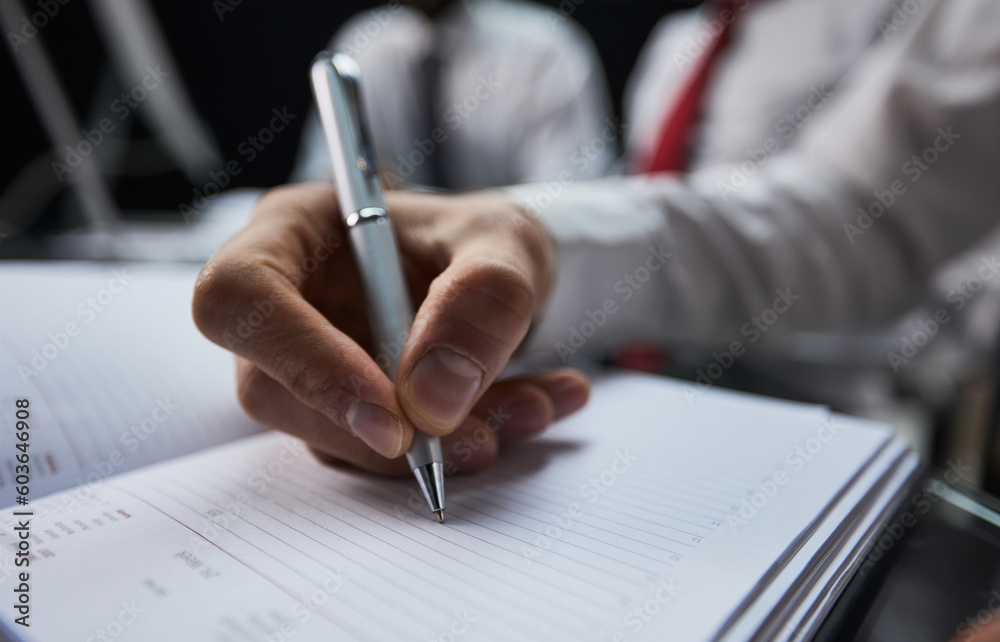 Businessman writes with a pen in diary, business and education concept. Close up Businessman writes with a pen in diary, business and education concept. Close up