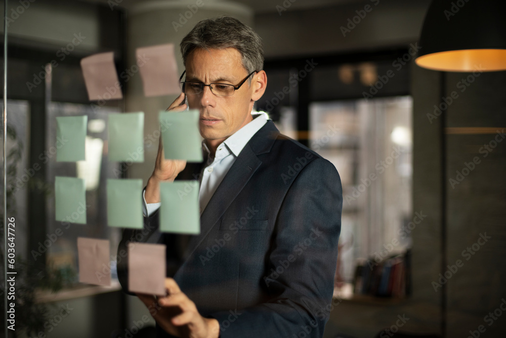 Portrait of successful businessman in office. Man writing ideas on colorful stickers on glass wall. Portrait of successful businessman in office. Man writing ideas on colorful stickers on glass wall.