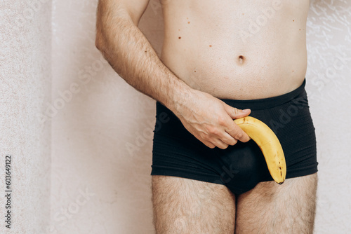 a guy without clothes holds a missing banana in his hand. Erection problem, male health photo