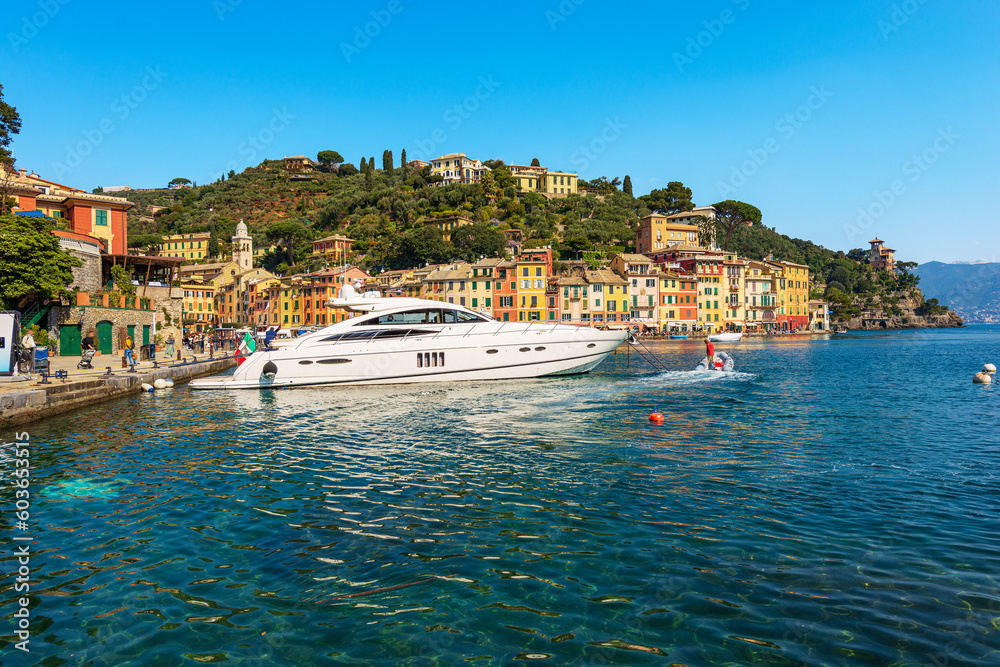 Cityscape and port of Portofino with a luxury yacht moored. Tourist resort in Genoa Province, Liguria, Italy, Europe. Colorful houses, Mediterranean sea (Ligurian sea).