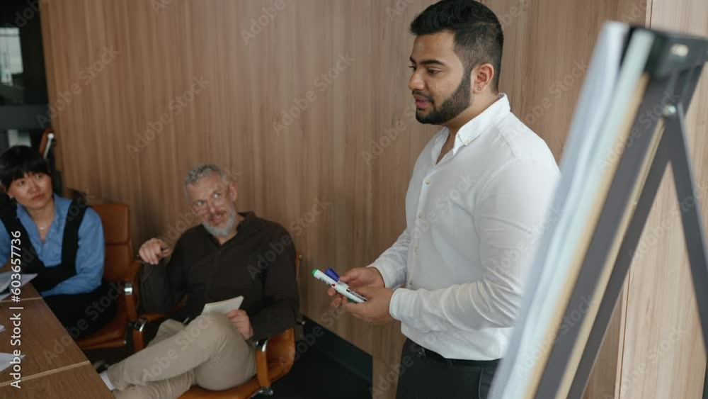 Positive indian worker answers colleagues questions at blackboard in office meeting