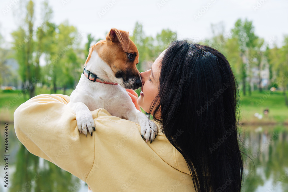 Woman and a dog close-up portraits. Woman holds a dog in her arms, hugs. Beautiful colorful summer natural landscape Woman and a dog close-up portraits. Woman holds a dog in her arms, hugs. Beautiful colorful summer natural landscape