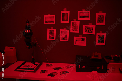 Workplace with equipment and photos on table in darkroom with red light photo