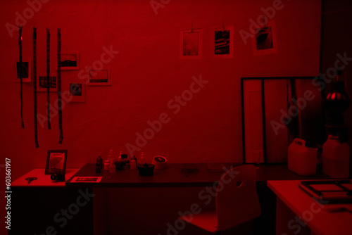 Workplace in darkroom with printed photos and photo film hanging above the table