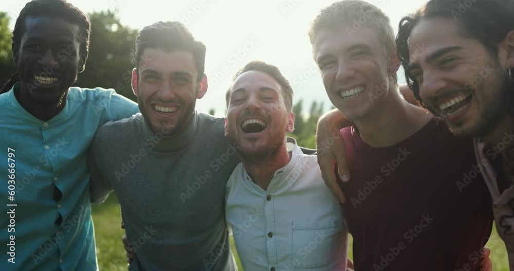 Happy male friends having fun together outdoor - Group of young men hugging each other at park while smiling on camera