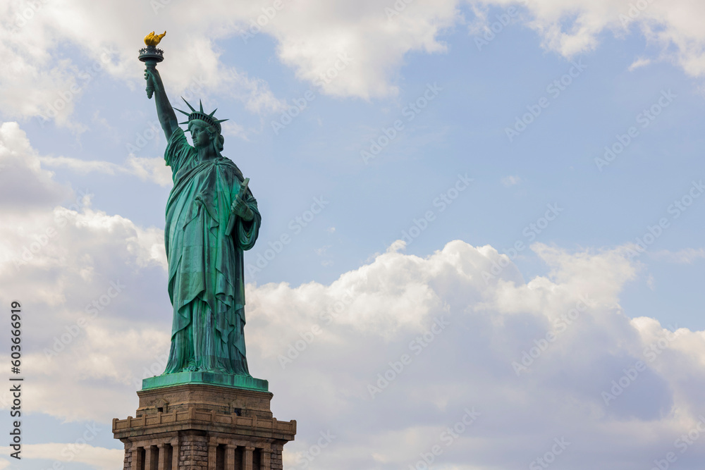 Beautiful view of Statue of Liberty on Liberty island in New York against on blue sky with white clouds background.