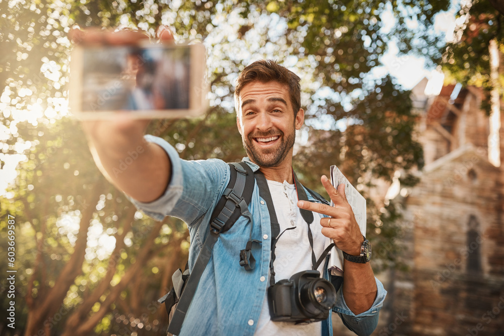 Fototapeta premium Happy man, tourist and peace sign selfie in a city for travel with holiday memory, smile and happiness. Male person outdoor on adventure, journey or vacation photo and freedom with a backpack