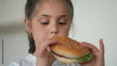 Child bites big burger with pleasure. Happy child eats unhealthy fast food. Juicy tasty burger. American way of life. Food addiction. quick snack for child with burger. Fast food concept photo
