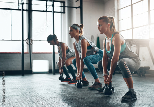 Kettlebell, fitness and women in a gym, training or workout goal with wellness, class or exercise. Female athlete, girls or squat with equipment, sports or relax with healthy lifestyle or challenge