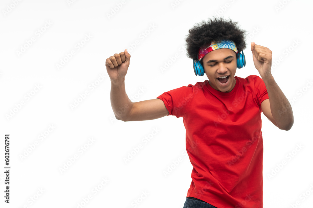 Naklejka premium African american guy in headphones looking enjoiyed and dancing