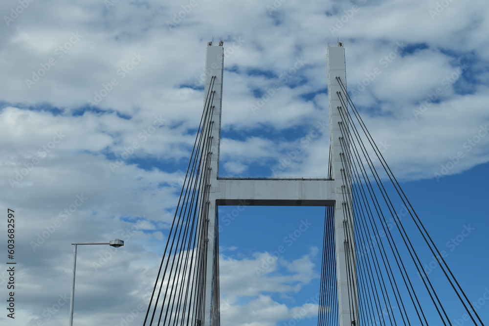 青い空白い雲海にかかる橋と走る車