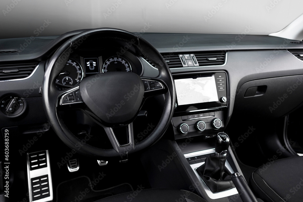 Modern black car interior, leather steering wheel, climate control, navigation, deflectors on the car panel. Details interior. 