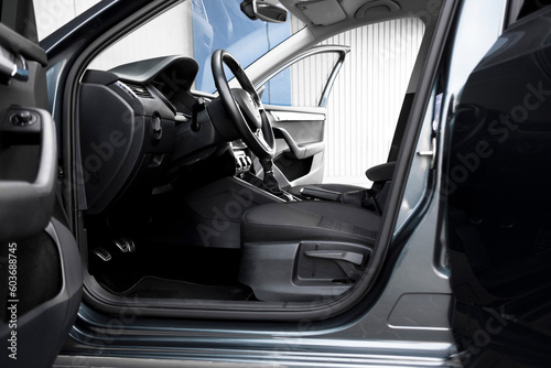 Modern black car interior, leather steering wheel, climate control, navigation, deflectors on the car panel. Details interior. 