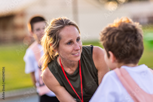 netball coach bending to talk to young player photo