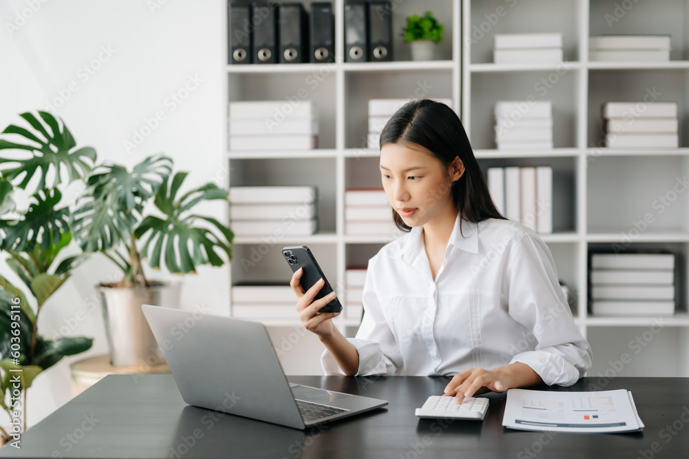 Asian businesswoman working in the modern office with working notepad, tablet and laptop documents Asian businesswoman working in the modern office with working notepad, tablet and laptop documents