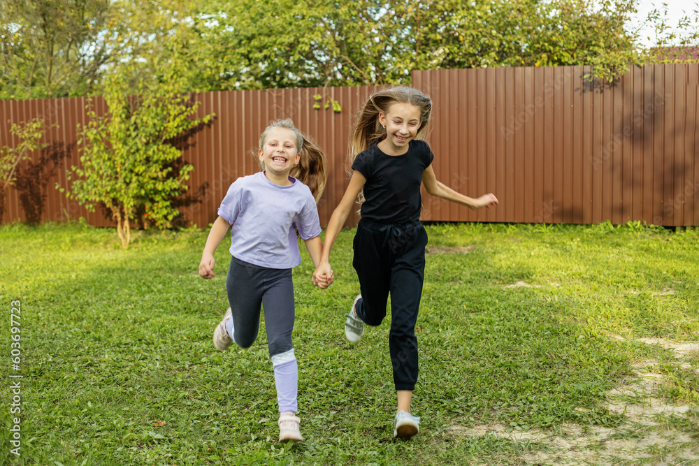 Two children run in backyard in summertime. Childhood and vacation concept. Two children run in backyard in summertime. Childhood and vacation concept.